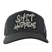 Black cap with 'SHIT HAPPENS' text in rhinestones on a counter.