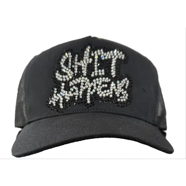 Black cap with 'SHIT HAPPENS' text in rhinestones on a counter.